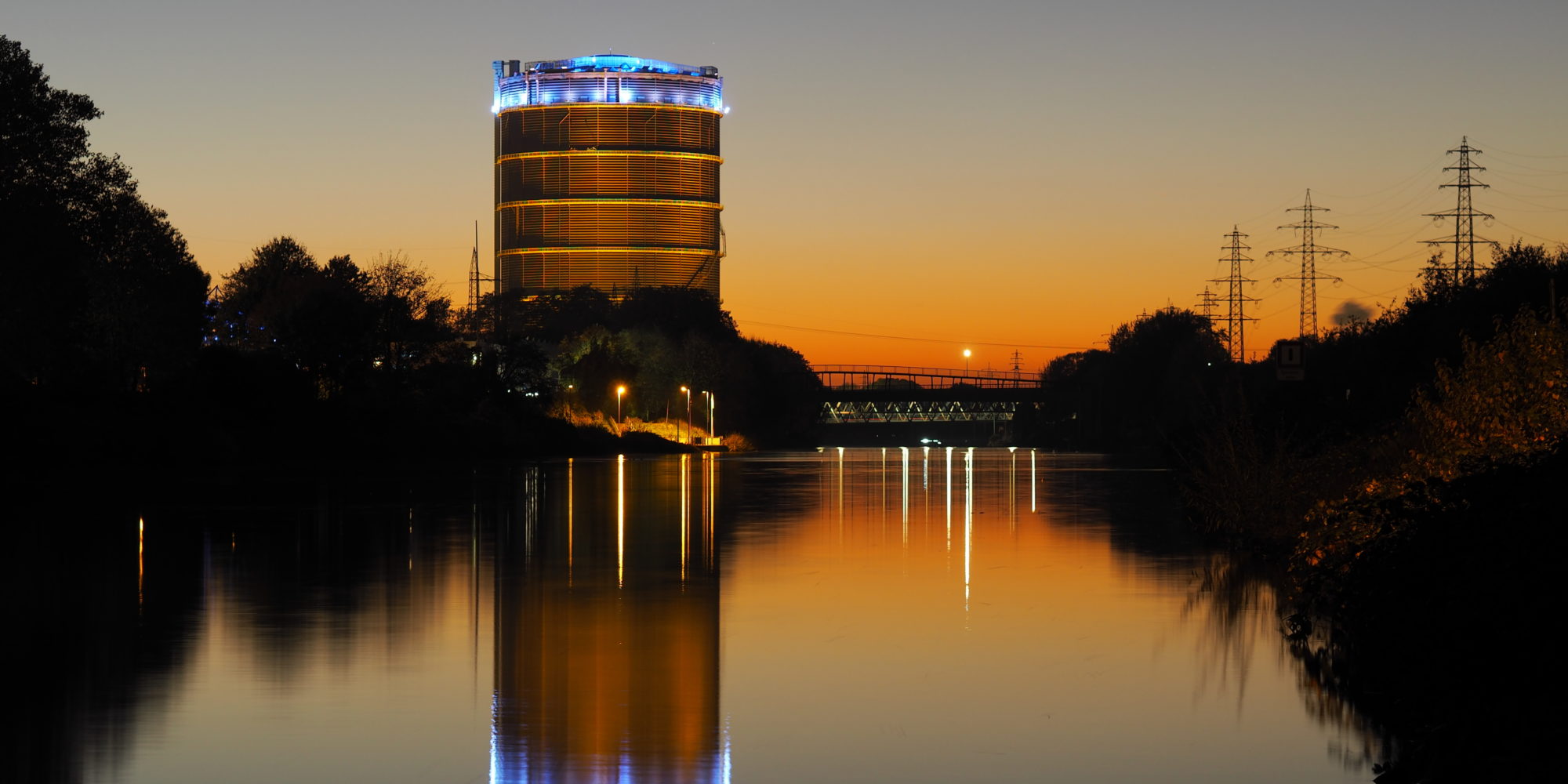 Das Foto zeigt den Gasometer Oberhausen samt Rhein-Herne-Kanal beim Sonnenuntergang