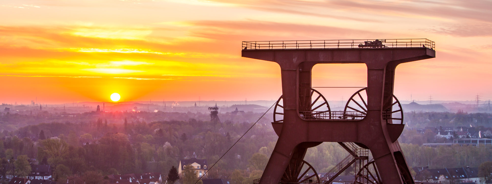 Das Foto zeigt das Fördergerüst des UNESCO-Welterbe Zollverein in Essen im Sonnenuntergang