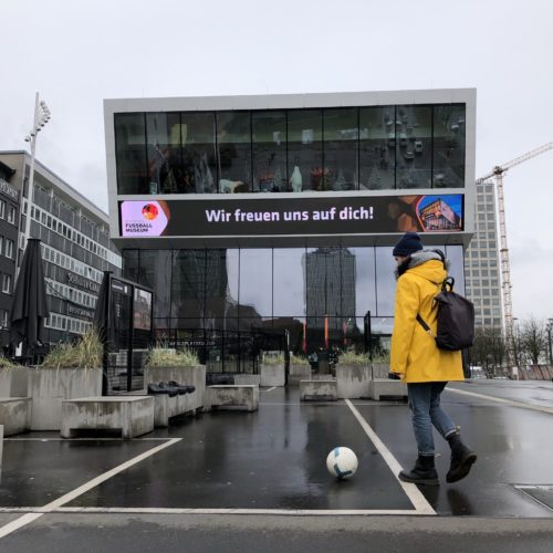 Das Bild zeigt eine fußballspielende Frau vor dem Deutschen Fußballmuseum in Dortmund