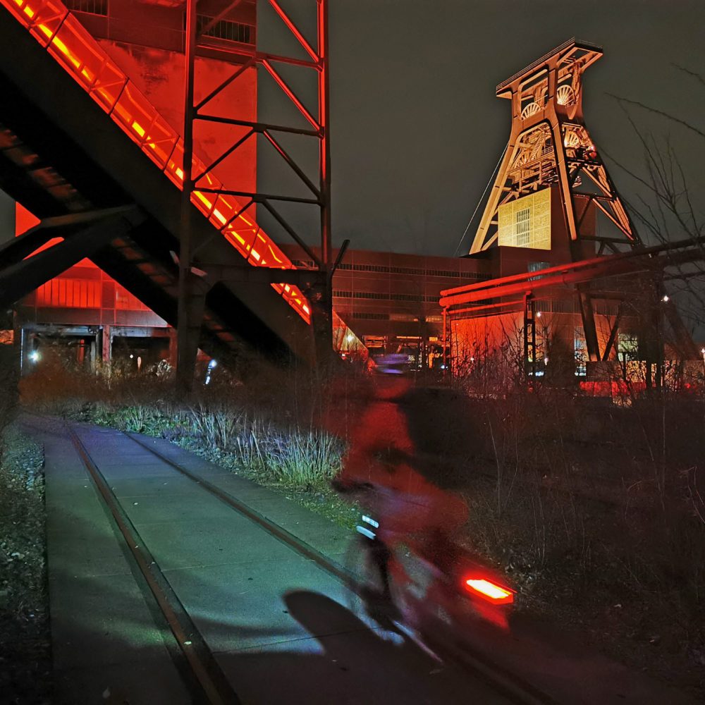 Das Foto zeigt einen Radfahrer an der Zeche Zollverein in Essen bei einem Nightride durchs Ruhrgebiet