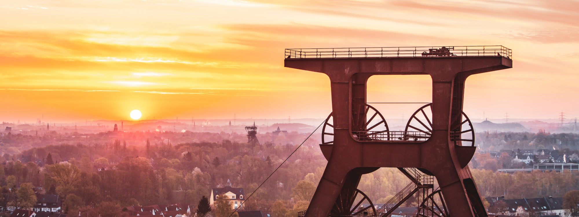 Zdjęcie przedstawia wieżę czołową wpisanego na Listę Światowego Dziedzictwa UNESCO Zollverein w Essen o zachodzie słońca