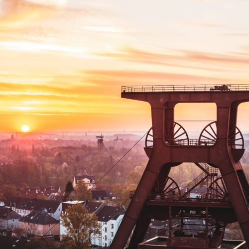 De foto toont het hoofdframe van het UNESCO-werelderfgoed Zollverein in Essen bij zonsondergang