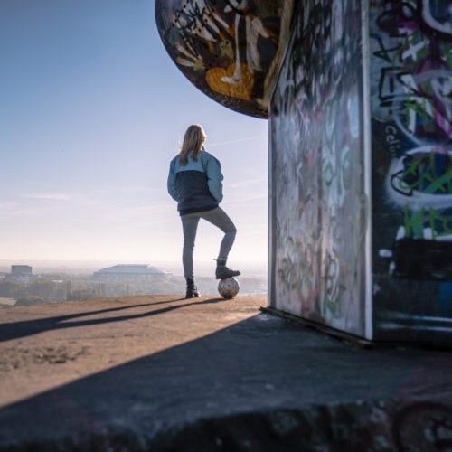 Das Bild zeigt eine Frau auf der Halde Rungenberg in Gelsenkirchen mit Blick zur Arena auf Schalke