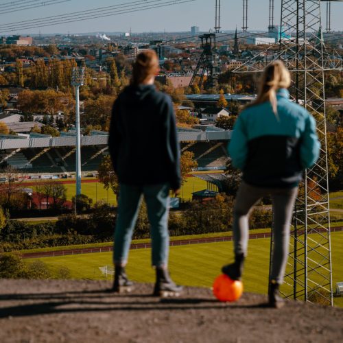 Das Bild zeigt zwei Frauen mit Fußball auf der Halde Rheinelbe in Gelsenkirchen mit Blick auf das Stadion des SG Wattenscheid 09
