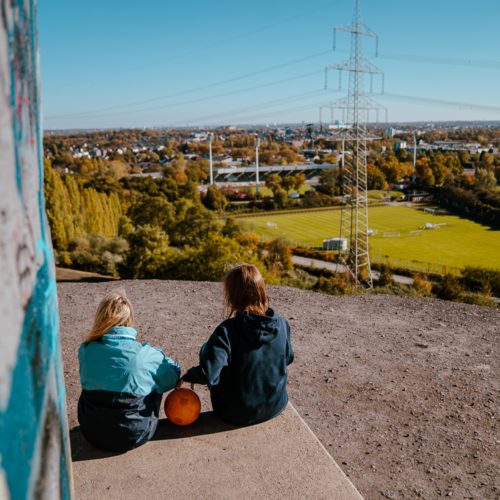 Das Bild zeigt zwei Menschen mit Fußball auf der Halde Rheinelbe mit Blick auf das Stadion von SG Wattenscheid 09