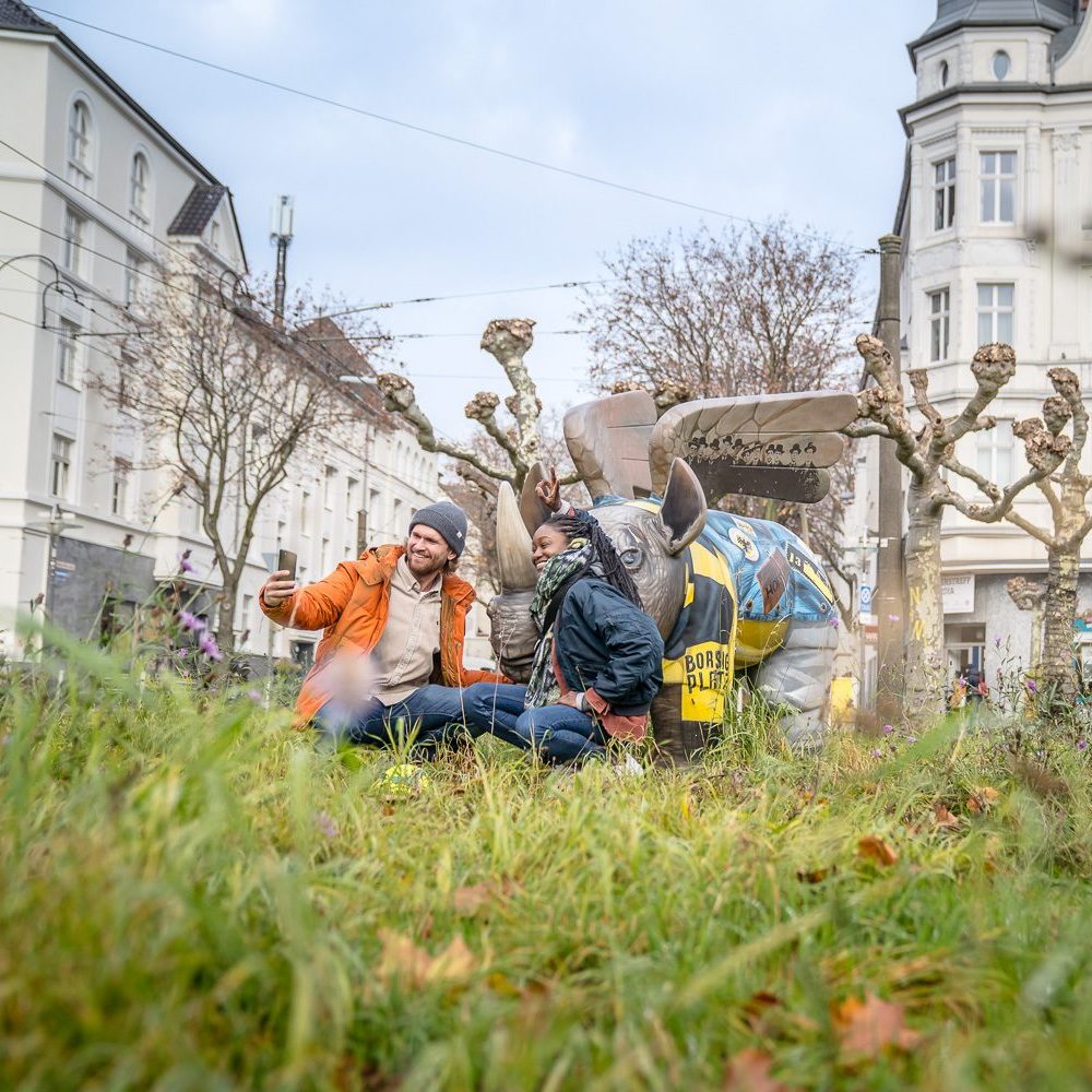 Das Bild zeigt ein Paar auf dem Borsigplatz in Dortmund, das mit dem Nilpferd posiert