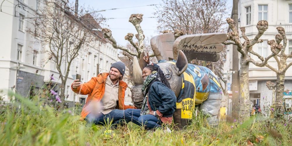 Das Bild zeigt ein Paar auf dem Borsigplatz in Dortmund, das mit dem Nilpferd posiert