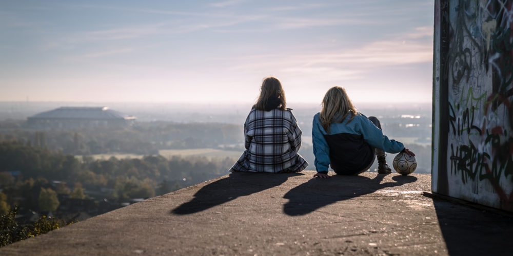 Das Bild zeigt zwei Menschen auf der Halde Rungenberg mit Blick auf das Stadion des FC Schalke 04